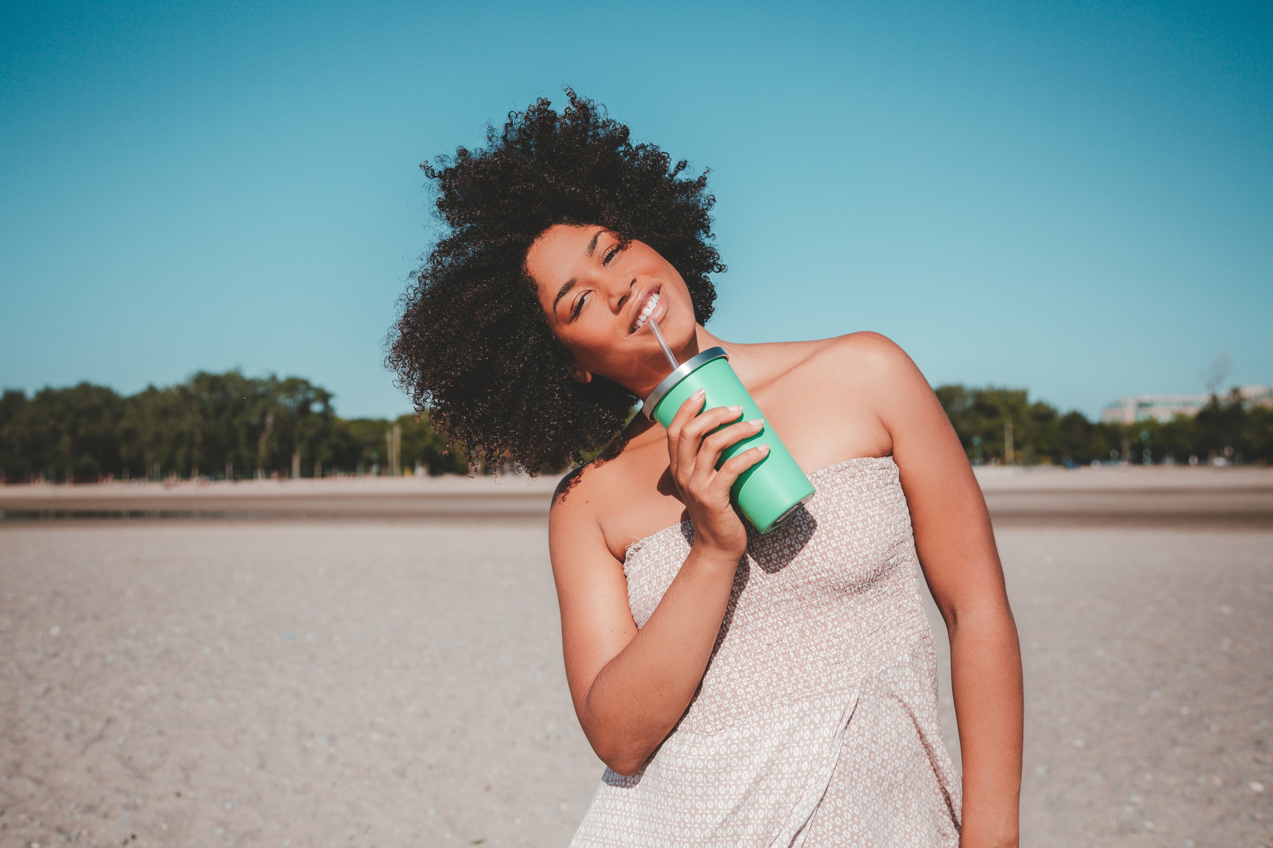 files/young-woman-holding-drink-cup-with-straw-on-sandy-beach.jpg